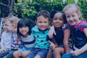 A group of children sit together and smile.