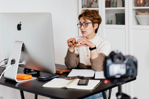 A woman takes a video call at her desk.