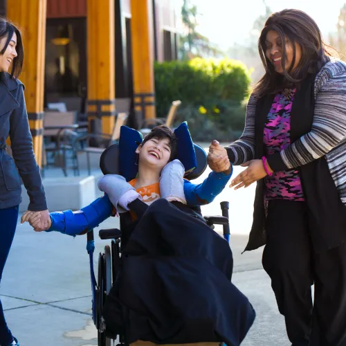 Two women and child in wheelchair enjoying the day outside