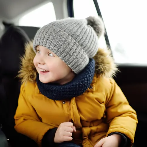 Bundled-up little boy in the backseat of a car, on his way to a parent's house.