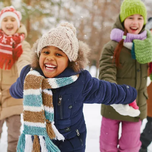 A group of children play together in the snow.