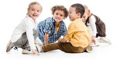 A group of smiling children sit on the floor playing