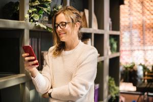 A woman smiles as she looks at her phone.