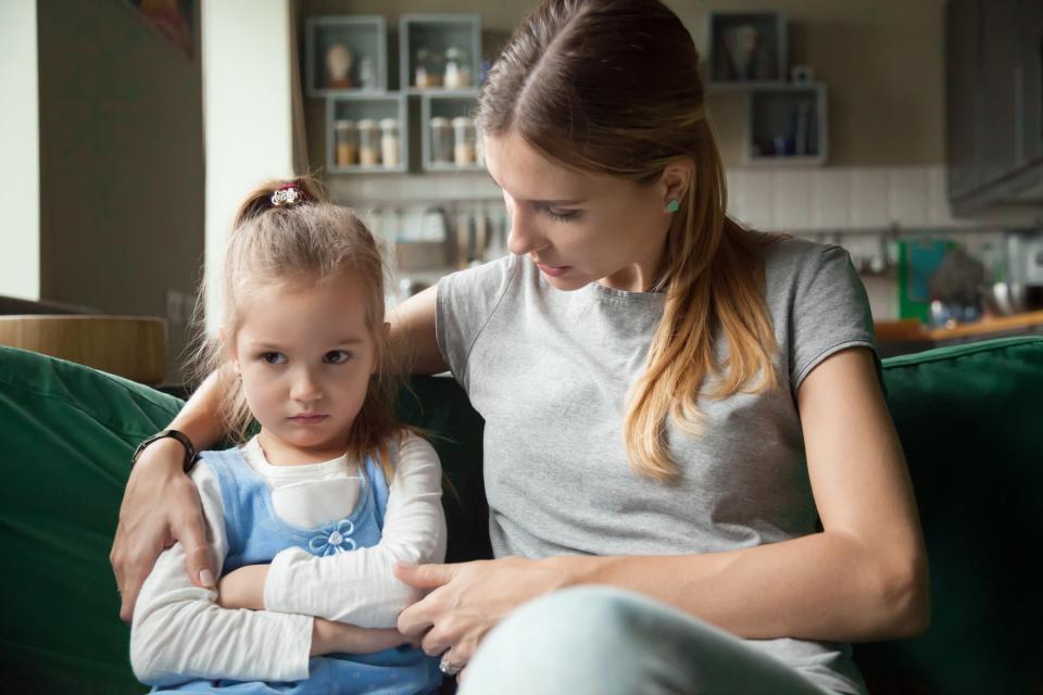 Mom consoles upset daughter on couch.